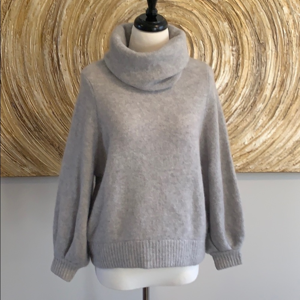 Grey turtleneck sweater with bell sleeves.